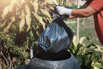 Wall Mural - hand holding garbage black bag putting in to trash