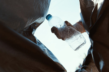 Wall Mural - hand putting empty plastic bottle in to garbage black bag