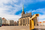 St. Bartholomew's Cathedral in the main square of Plzen with a fountain on the foreground against blue sky and clouds sunny day. Czech Republic, Pilsen. Famous landmark in Czech Republic, Bohemia.