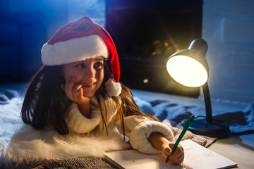 Wall Mural - Little girl writes letter to Santa near christmas