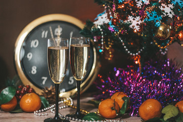 Christmas composition consisting of watches, glasses of champagne with bubbles, decorated Christmas tree, tangerines and other decorations