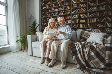 Wall Mural - Senior couple together at home retirement concept using digital tablet pointing at screen