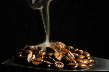 Coffee beans with fresh roasted beans smoke it on a tin plate