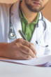 © MirBasar - A doctor writing a prescription with a stethoscope hanging around his neck
