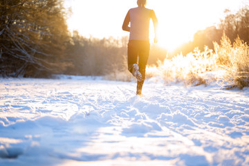 Image from back of man in sportswear, red cap on run in winter