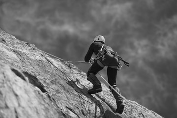 Wall Mural - The climber climbs up the rock wall. Black and white.