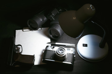 Wall Mural - blank page, pen, film photo camera, handgun and a binoculars on a black detective agent table backgr