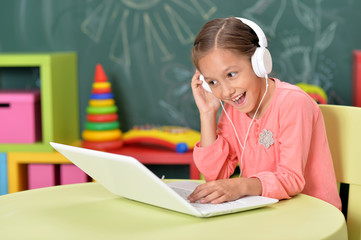 Wall Mural - Girl in headphones using laptop in classroom