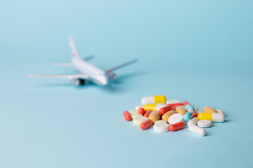 airplane model with multi-colored pills from motion sickness scattered on a blue background. concept nausea in the plane