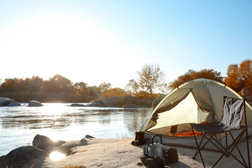 camping equipment near tent with sleeping bag outdoors