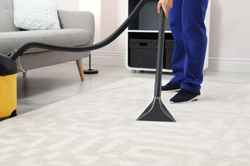 Wall Mural - Man removing dirt from carpet with vacuum cleaner indoors, closeup. Space for text