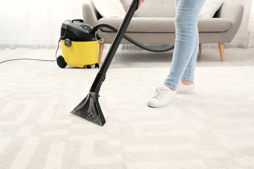 Wall Mural - Woman removing dirt from carpet with vacuum cleaner indoors, closeup