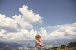 © sonyachny - Stylish hipster girl in hat walking on top of sunny mountains. Happy young woman exploring in summer mountains and looking at sky. Travel and wanderlust concept.