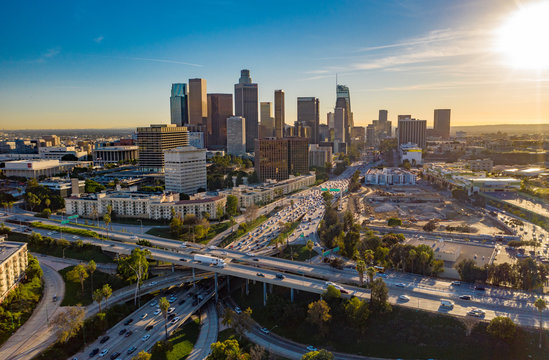 drone view of downtown los angeles or la skyline with skyscrapers and freeway traffic below.