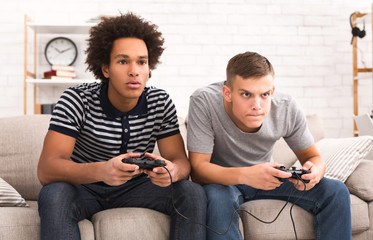 Focused teens playing video games together on couch