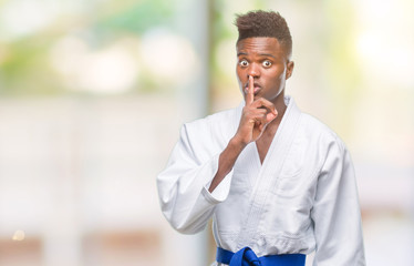 Sticker - Young african american man over isolated background wearing kimono asking to be quiet with finger on lips. Silence and secret concept.