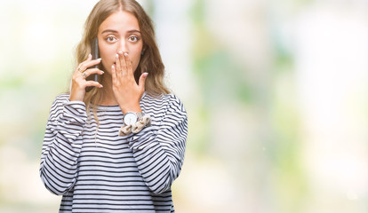 Canvas Print - Beautiful young blonde woman talking on smarpthone over isolated background cover mouth with hand shocked with shame for mistake, expression of fear, scared in silence, secret concept