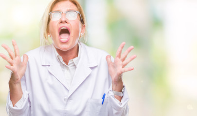 Canvas Print - Middle age blonde therapist woman wearing white coat over isolated background crazy and mad shouting and yelling with aggressive expression and arms raised. Frustration concept.