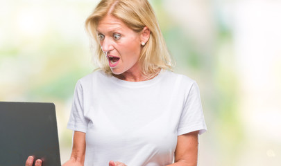 Sticker - Middle age blonde woman using computer laptop over isolated background scared in shock with a surprise face, afraid and excited with fear expression