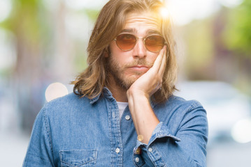 Sticker - Young handsome man with long hair wearing sunglasses over isolated background thinking looking tired and bored with depression problems with crossed arms.