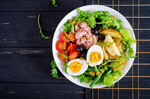 Healthy Hearty Salad Of Tuna, Green Beans, Tomatoes, Eggs, Potatoes, Black Olives Close-up In A Bowl On The Table. Salad Nicoise. French Cuisine. Top View. Flat Lay