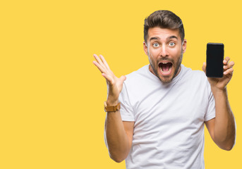 Sticker - Young handsome man showing smartphone screen over isolated background very happy and excited, winner expression celebrating victory screaming with big smile and raised hands