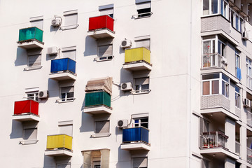 Architectural detail and pattern of modern residential building with colorful balconies and windows of apartments. Portrait of new urban city building facade with glass balconies of various colors.