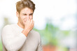 © Krakenimages.com - Young handsome man over isolated background smelling something stinky and disgusting, intolerable smell, holding breath with fingers on nose. Bad smells concept.