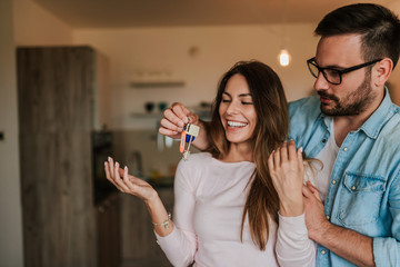 Wall Mural - Attractive young man surprising his wife with a key to their new apartment.