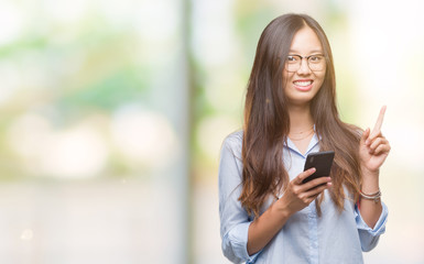 Poster - Young asian woman texting using smartphone over isolated background surprised with an idea or question pointing finger with happy face, number one