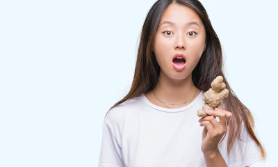 Poster - Young asian woman holding fresh organic over isolated background scared in shock with a surprise face, afraid and excited with fear expression