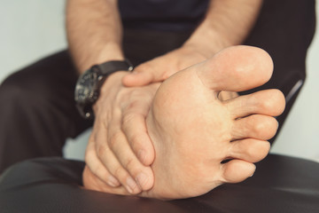 Jogger hands on foot. He is feeling pain as his ankle or foot is broken or twisted. Accident on running track during the morning exercise. Sport accident and foot sprain concepts