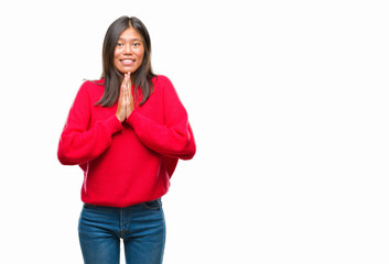 Sticker - Young asian woman wearing winter sweater over isolated background praying with hands together asking for forgiveness smiling confident.