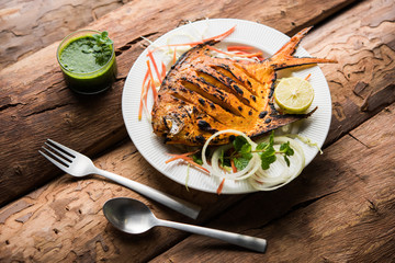 Wall Mural - Tandoori Pomfret fish cooked in a clay oven and garnished with lemon , mint, cabbage and carrot salad. Selective focus