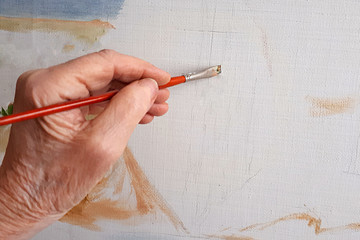  hand of an elderly person paints a picture with a brush