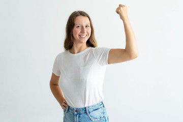 Wall Mural - Cheerful young woman pumping fist and celebrating achievement. Pretty girl looking at camera. Achievement concept. Isolated front view on white background.