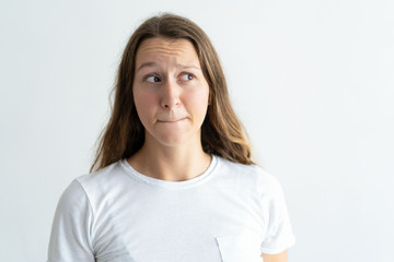 Sticker - Embarrassed young woman pursing mouth. Lady looking away. Bewilderment concept. Isolated front view on white background.