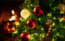 Christmas Tree Close Up On Blurred Burning Fireplace Background