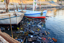 Old Boats Moored In Dirty Harbour. Pollution Of River, Sea, Ocean Water With Waste, Plastics Garbage. Concept Of Pollution Of Ocean, Sea And River Coastline With Plastic Trash