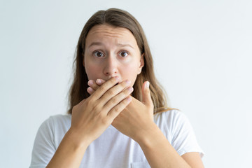 Sticker - Worried woman covering mouth with hands. Pretty lady looking at camera. Embarrassment concept. Isolated front view on white background.