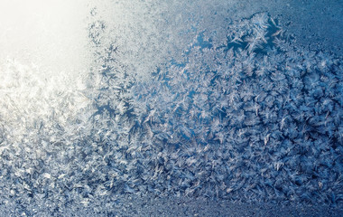 Christmas natural background with a frosty pattern on the winter glass illuminated by sunlight