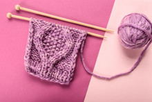 Flat Lay With Purple Yarn Ball And Knitting Needles On Pink And Purple Backdrop