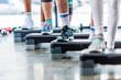 © LIGHTFIELD STUDIOS - partial view of sportspeople doing exercise on step platforms at gym