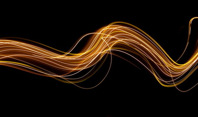 Long exposure light painting photography, curvy lines of vibrant neon metallic yellow gold against a black background