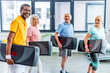 © LIGHTFIELD STUDIOS - laughing multiethnic sportspeople holding step platforms at gym