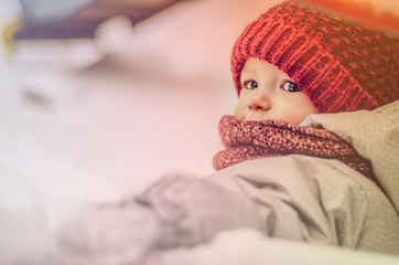 Canvas Print - Funny little child girl wearing in red hat, a scarf, and a warm winter suit with gloves having fun at winter day in beautiful winter park playing with snow. Copy space