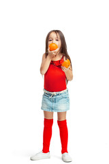 Wall Mural - Full length portrait of cute little kid girl in stylish jeans clothes with orange standing against white studio wall. Kids fashion concept