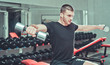 © splitov27 - Athletic young man exercising his shoulders and doing side raises with pair of dumbbells at gym