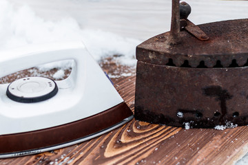 Ancient iron iron for ironing coals. Iron. on wooden background. and the meeting of a new era.