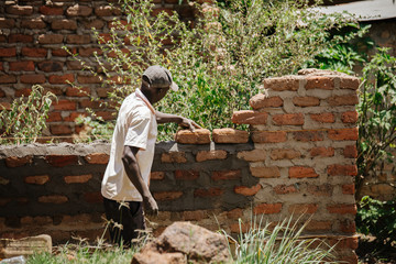 Wall Mural - man building a house in Uganda, Africa